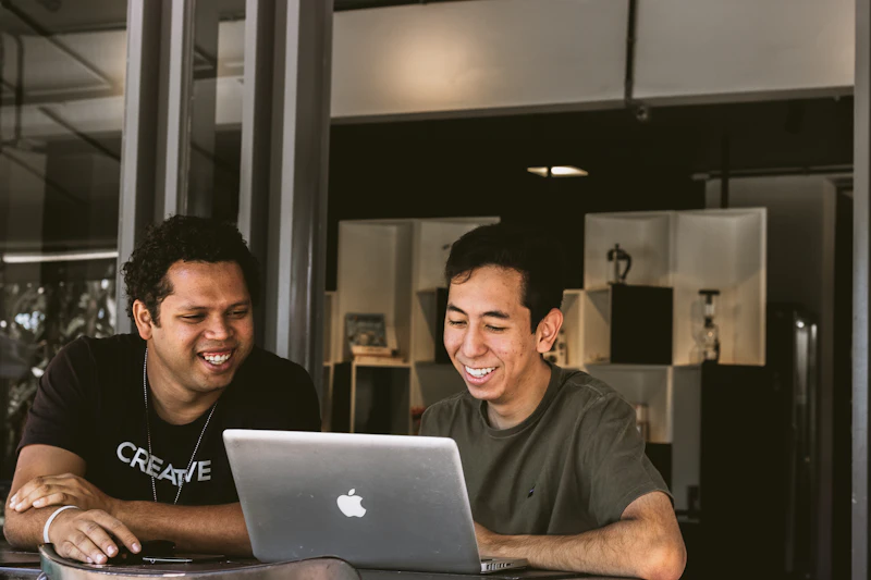 Dois empreendedores sorrindo enquanto olham juntos para um notebook